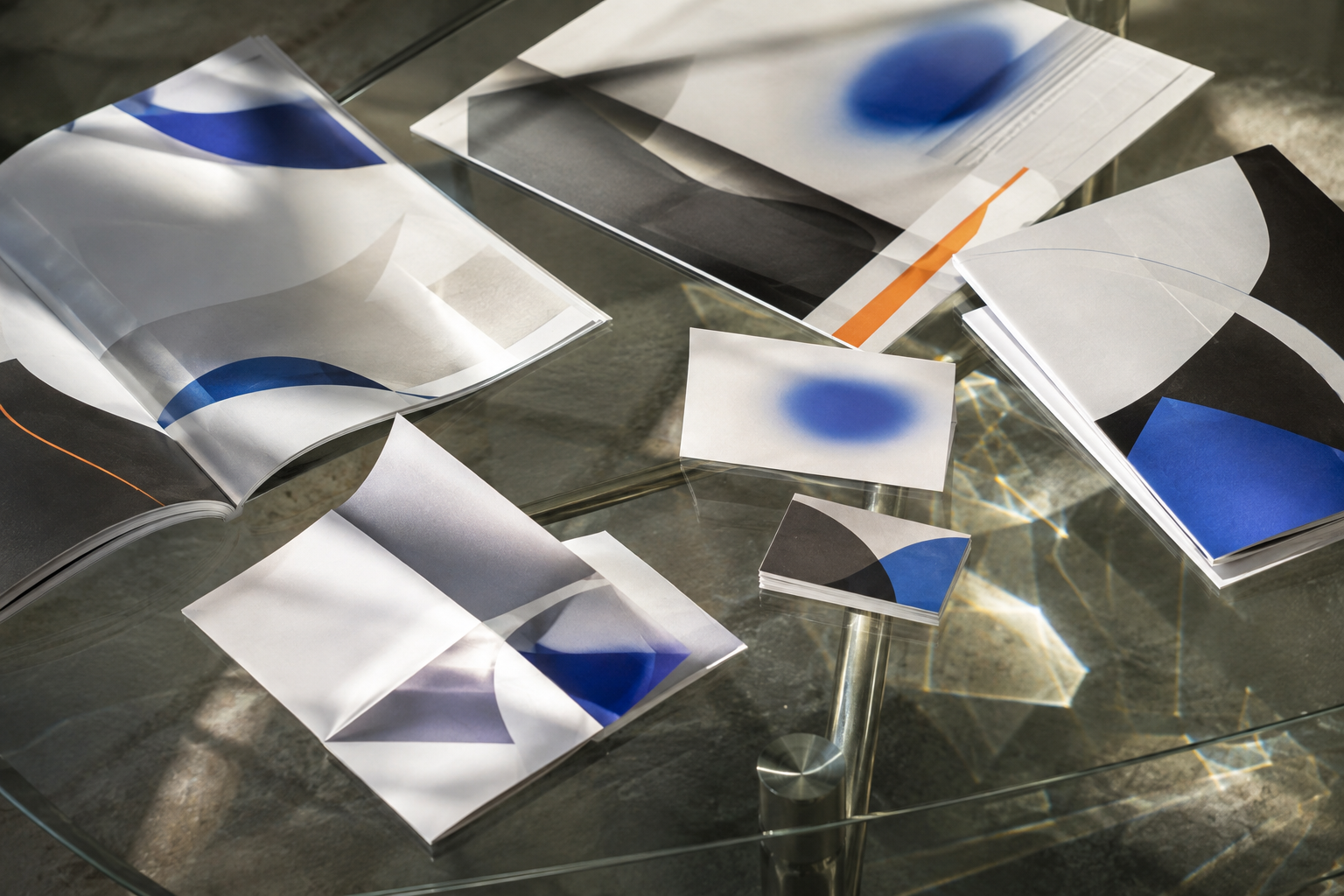 Brochures, cards, and print pieces arranged on a glass worktable